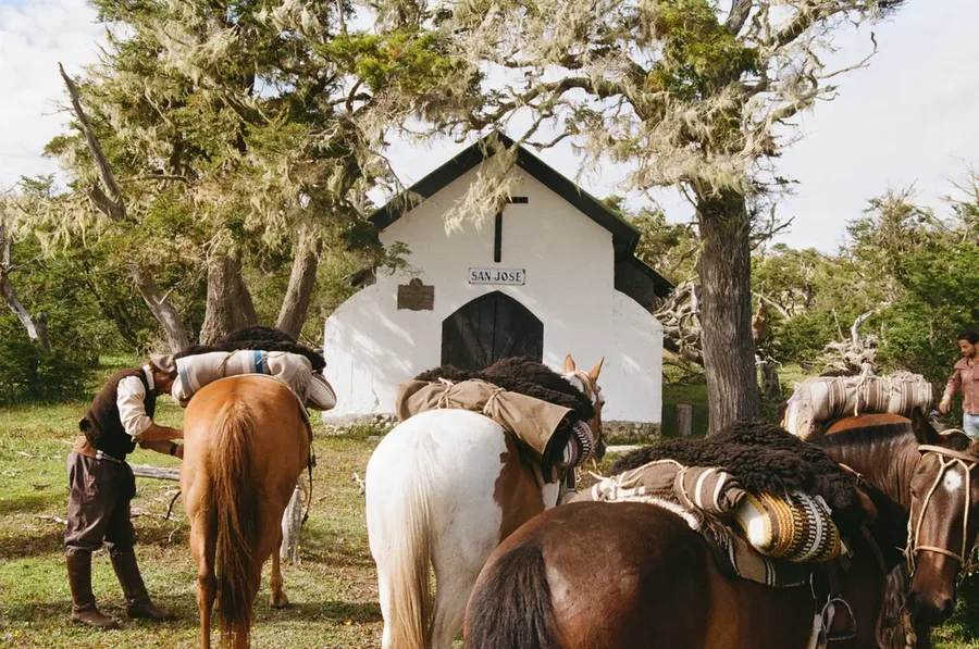 Pack horses gathered before a chapel.