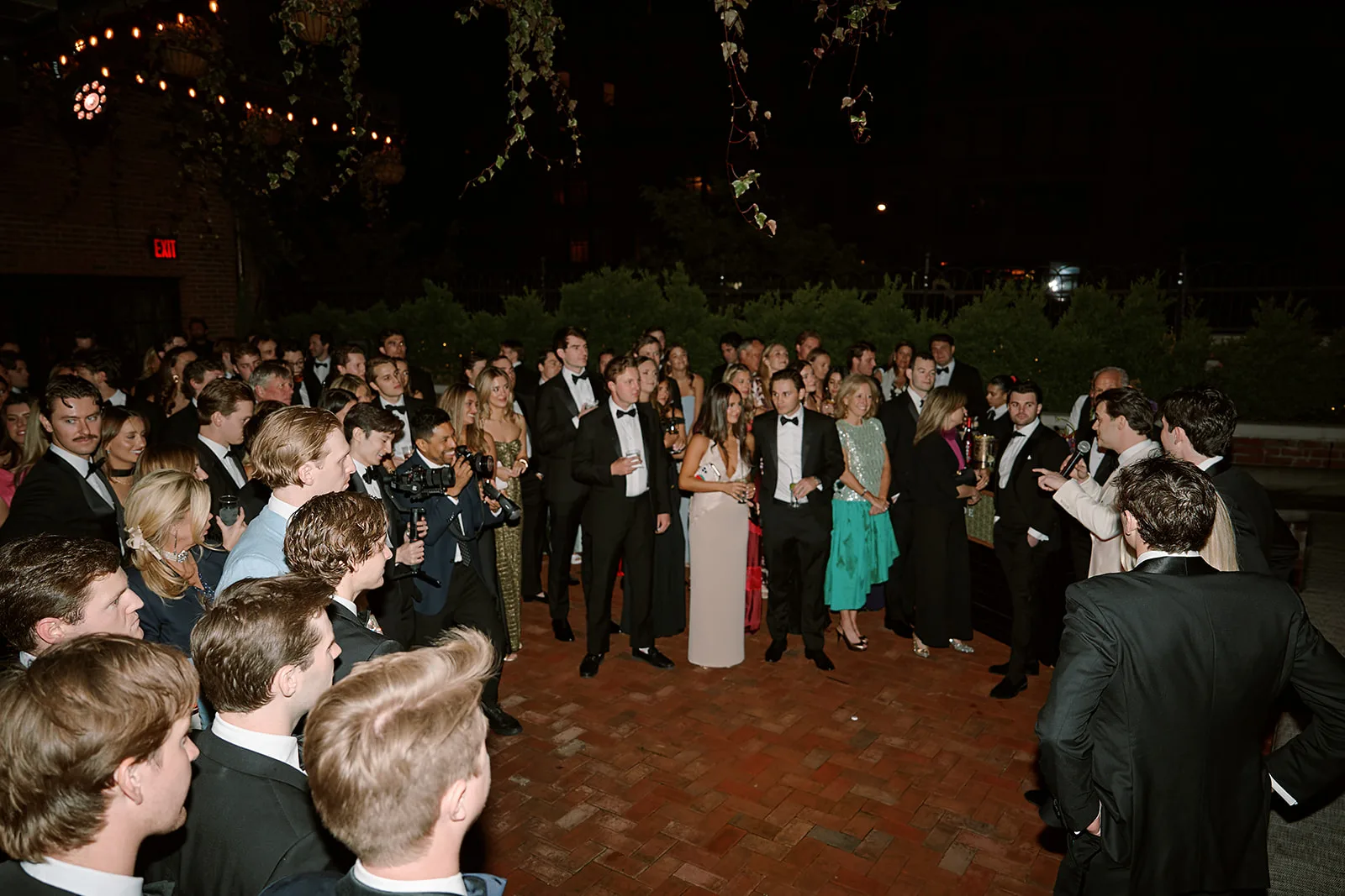 The full crowd gathered at night on the terrace, listening to a toast.
