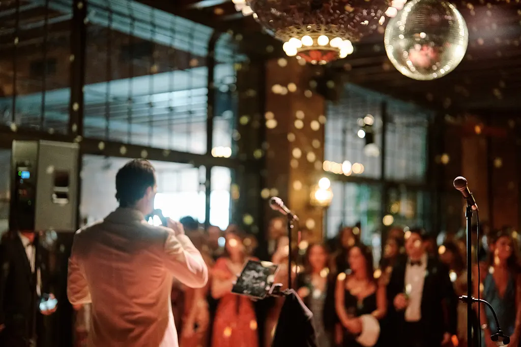 The singer over the dance floor, disco ball overhead.