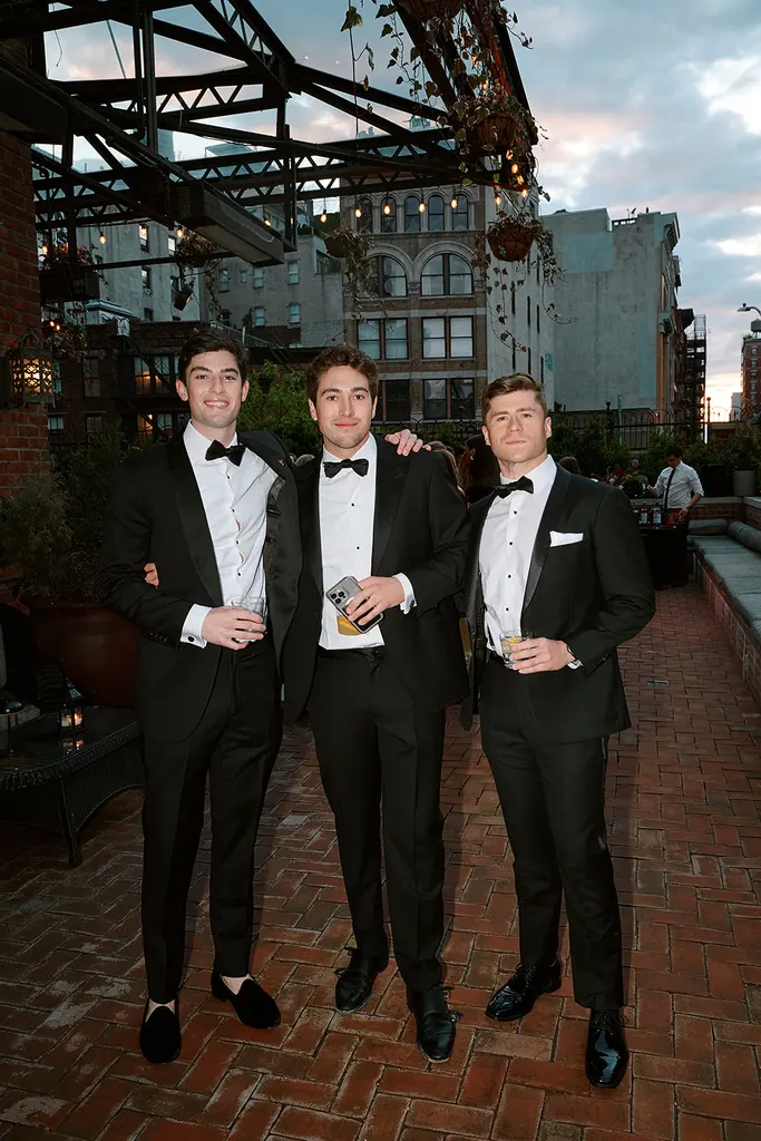 Three guests on the terrace at dusk, the downtown skyline behind them.