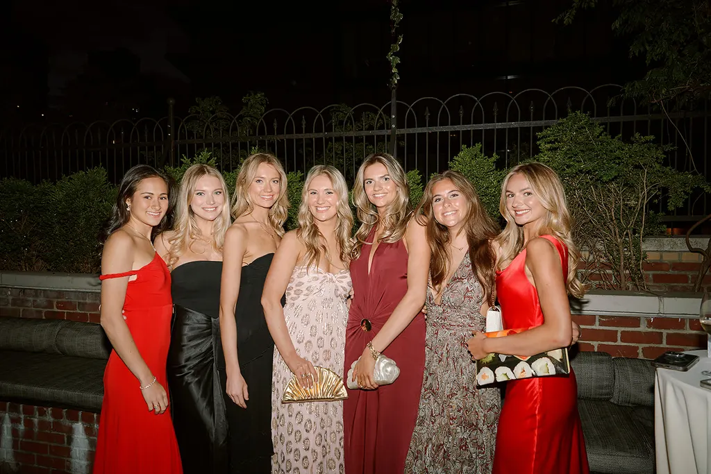 Guests in evening gowns, arm in arm.