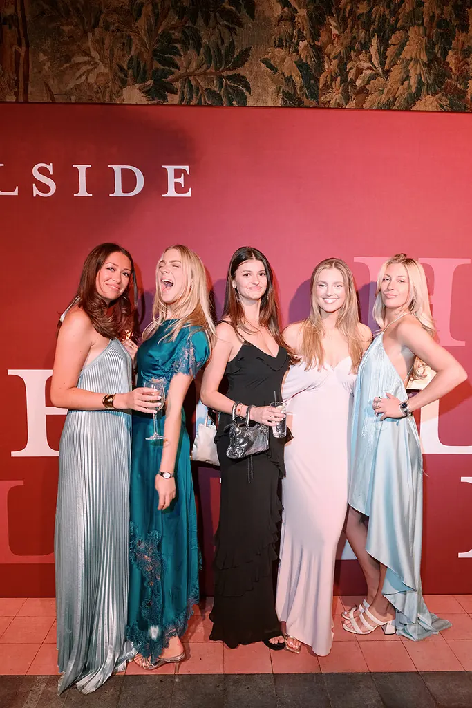 Five guests in gowns at the red Hillside wall.